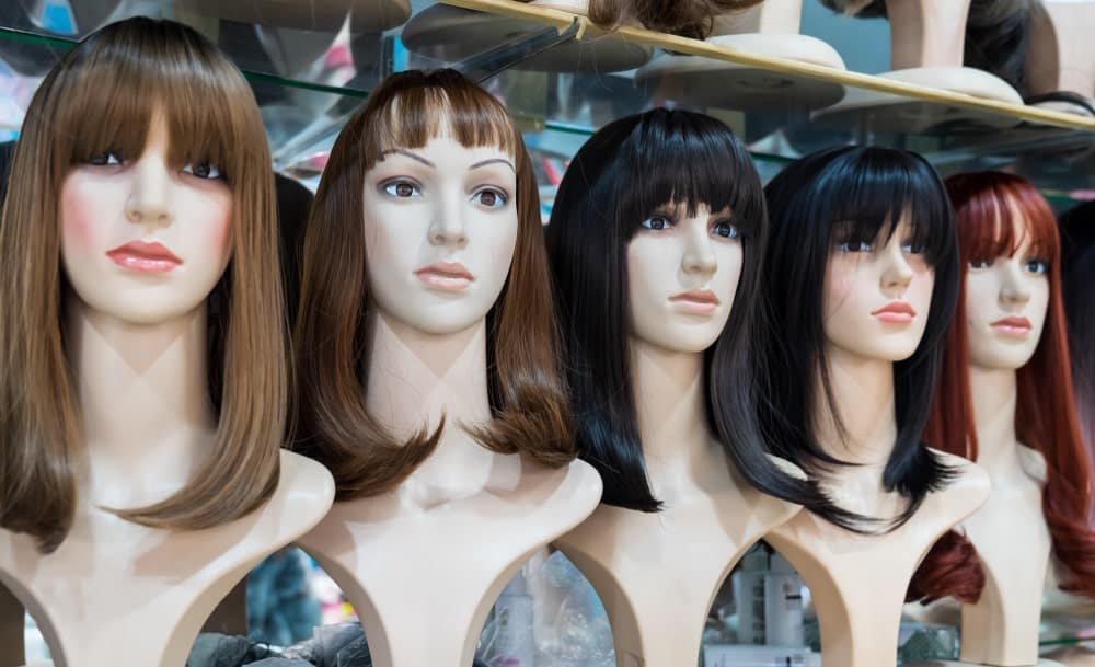 A row of various shoulder-length wigs on display.
