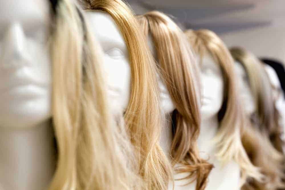 A row of long-haired wigs on display.