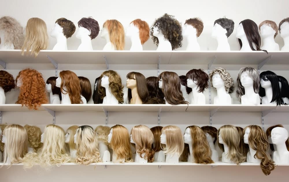 Display shelves filled with mannequin heads wearing various styles of wigs.