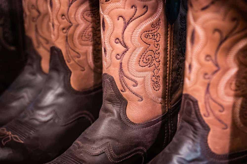 A close look at a collection of brown leather handmade cowboy boots.