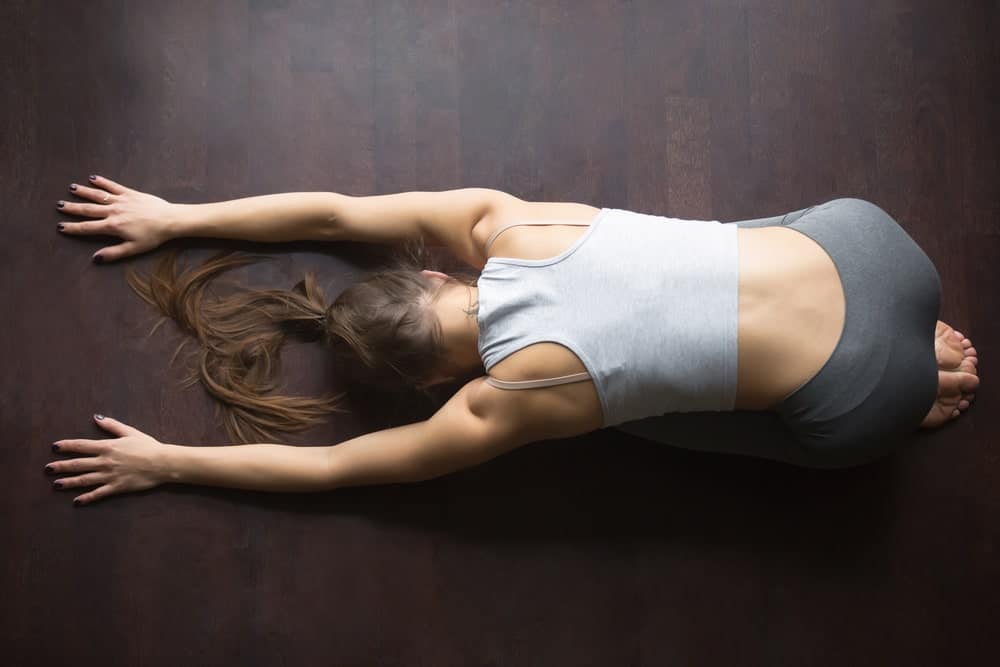 Top view of a woman doing a yoga position on the floor.