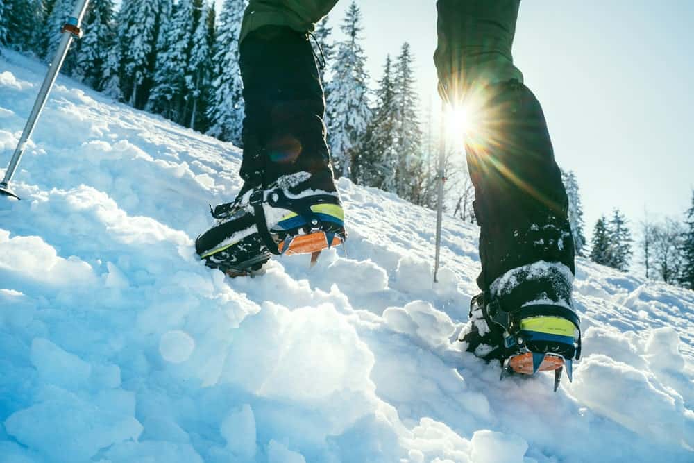 A man wearing a pair of mountaineering boots on a snowy mountain.