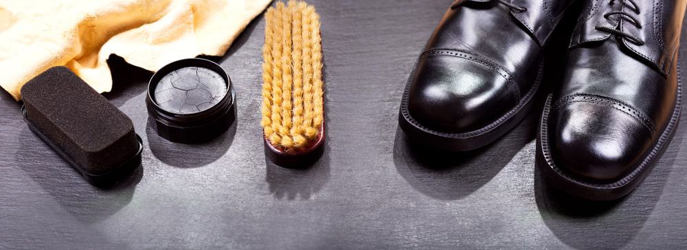 A close look at a pair of leather shoes with a set of wax shoe polish.