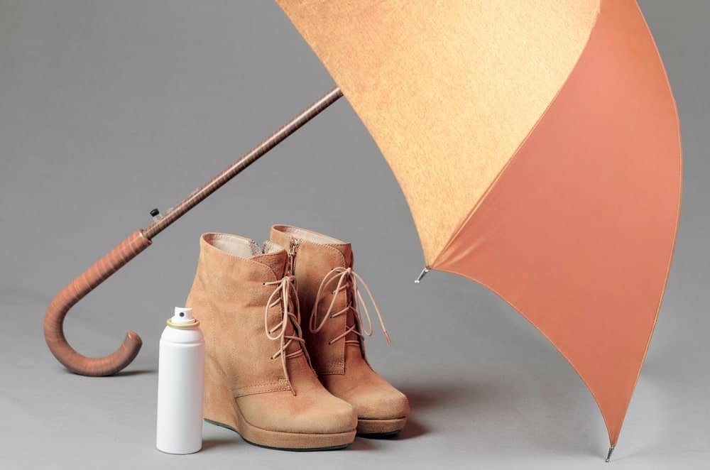 A pair of leather shoes with an umbrella and a leather conditioner.