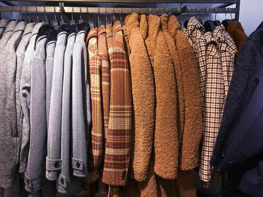 Various coats and jackets on hangers in a store.