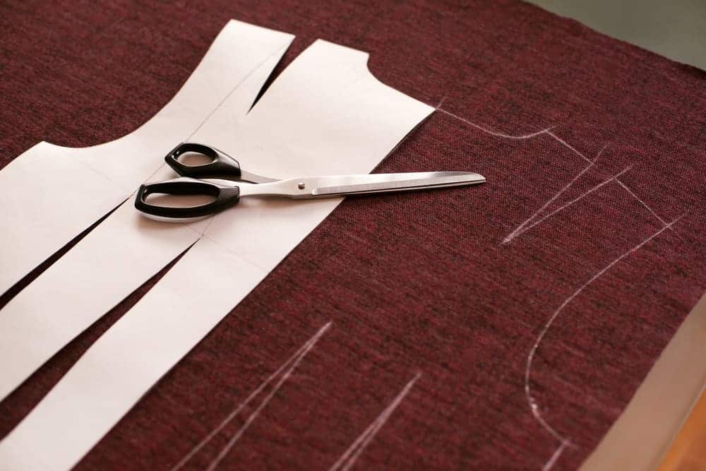 Cut out sewing pattern and tailoring scissors over a brown fabric.