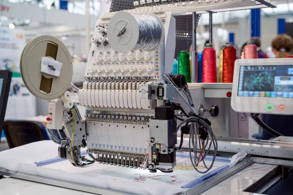 Automatic industrial sewing machine with display monitor and colorful threads.