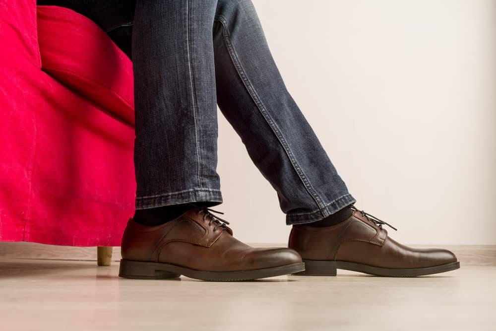 This is a close look at a man wearing a pair of jeans and a pair of dress shoes.