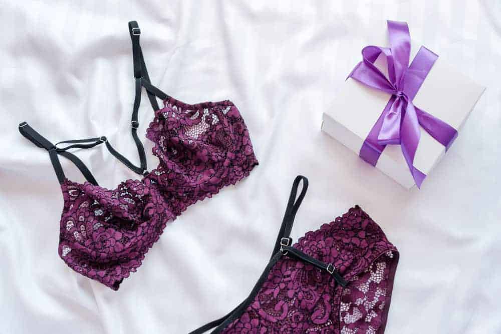 A pair of purple lingerie set as a gift on the bed.