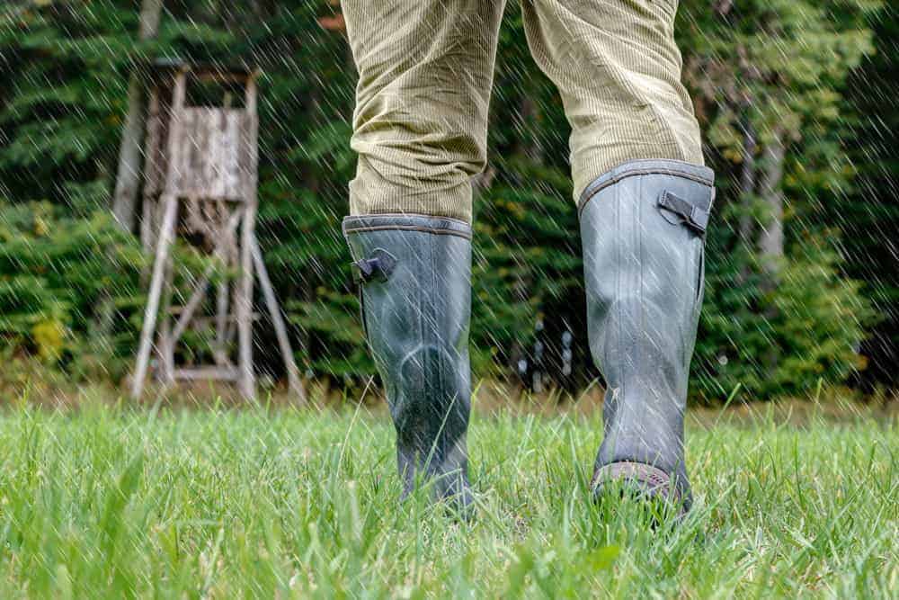 Hunter in green rubber boots walking through the rain.