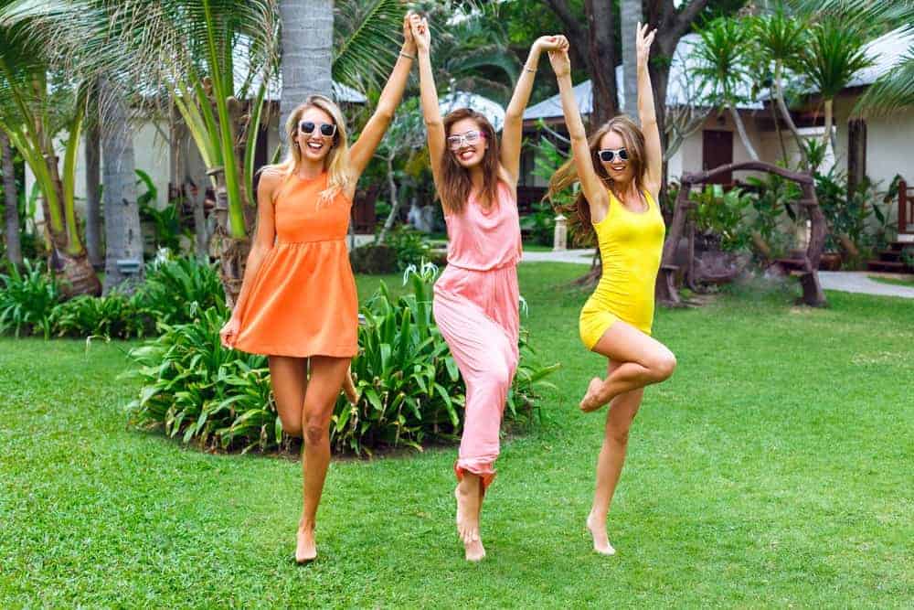 Three women wearing colorful summer outfits at a beach resort.