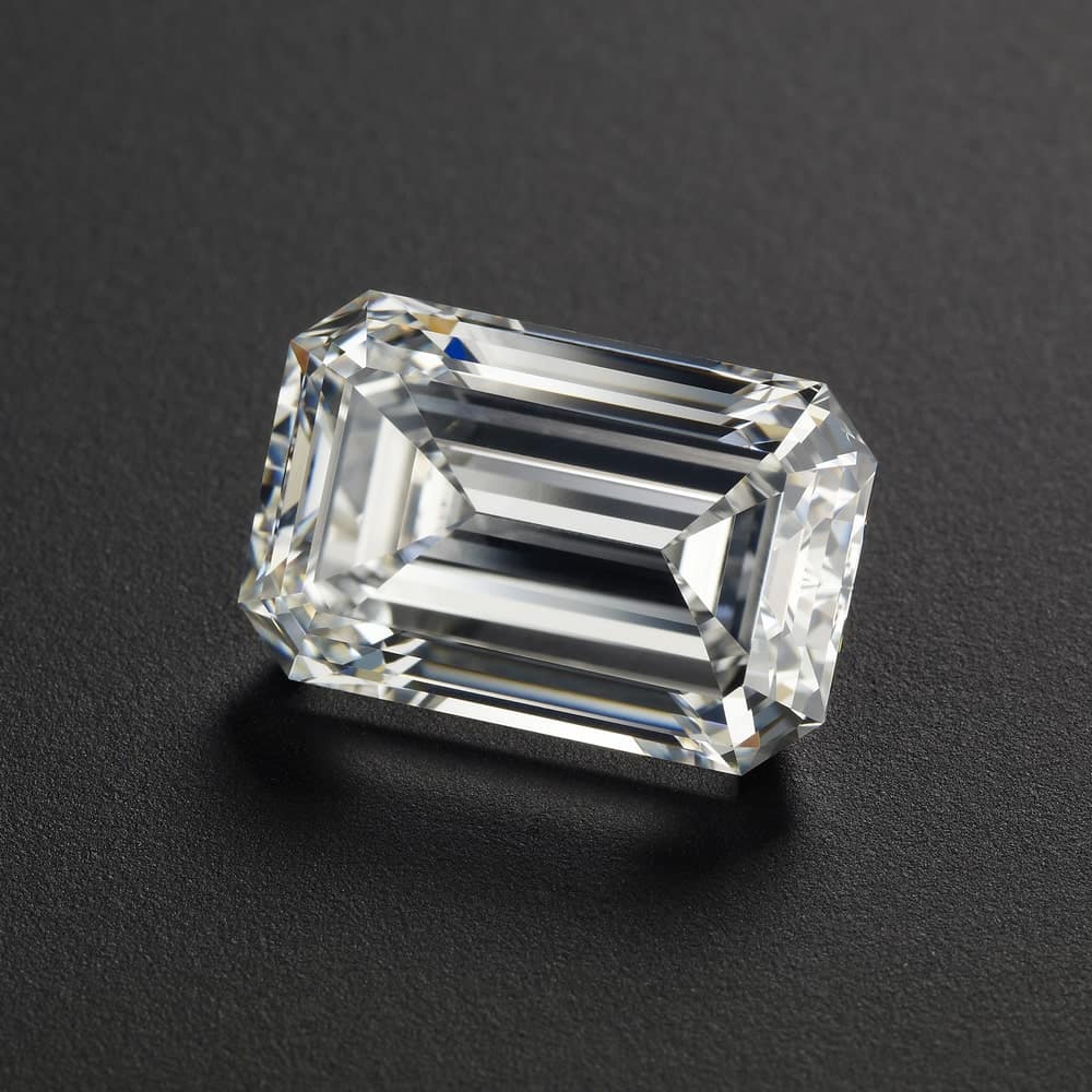 This is a close look at an emerald cut diamond on a dark surface.