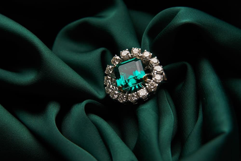 This is a close look at a ring with a large emerald surrounded by diamonds.