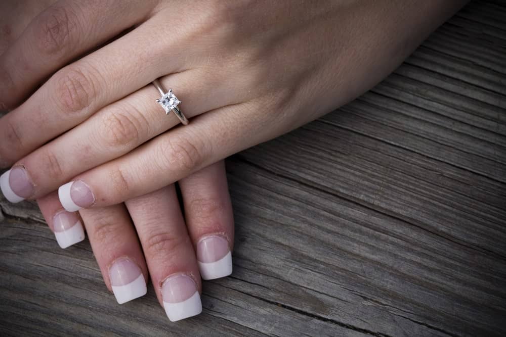 This is a close look at a woman's hands wearing a princess cut ring.