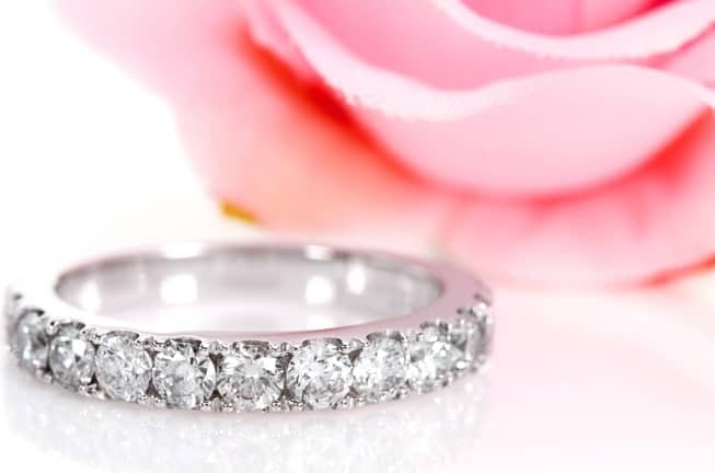 This is a close look at an eternity band with diamonds on a white surface.