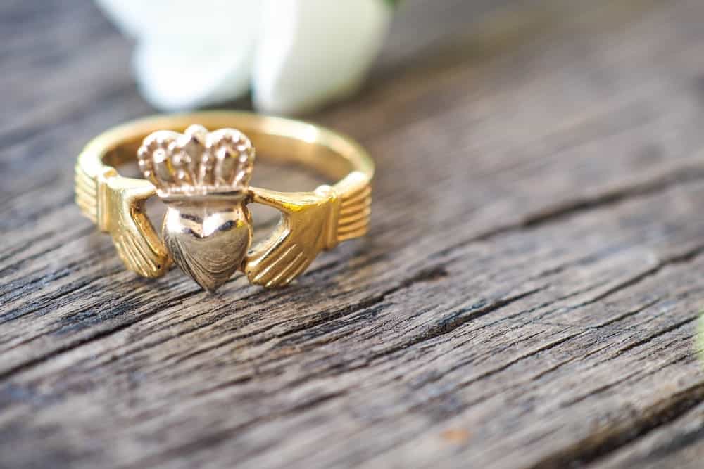This is a close look at a Claddagh Ring on a wooden table.