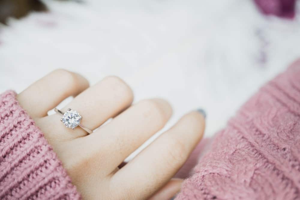 This is a close look at a woman's hand wearing an engagement ring.