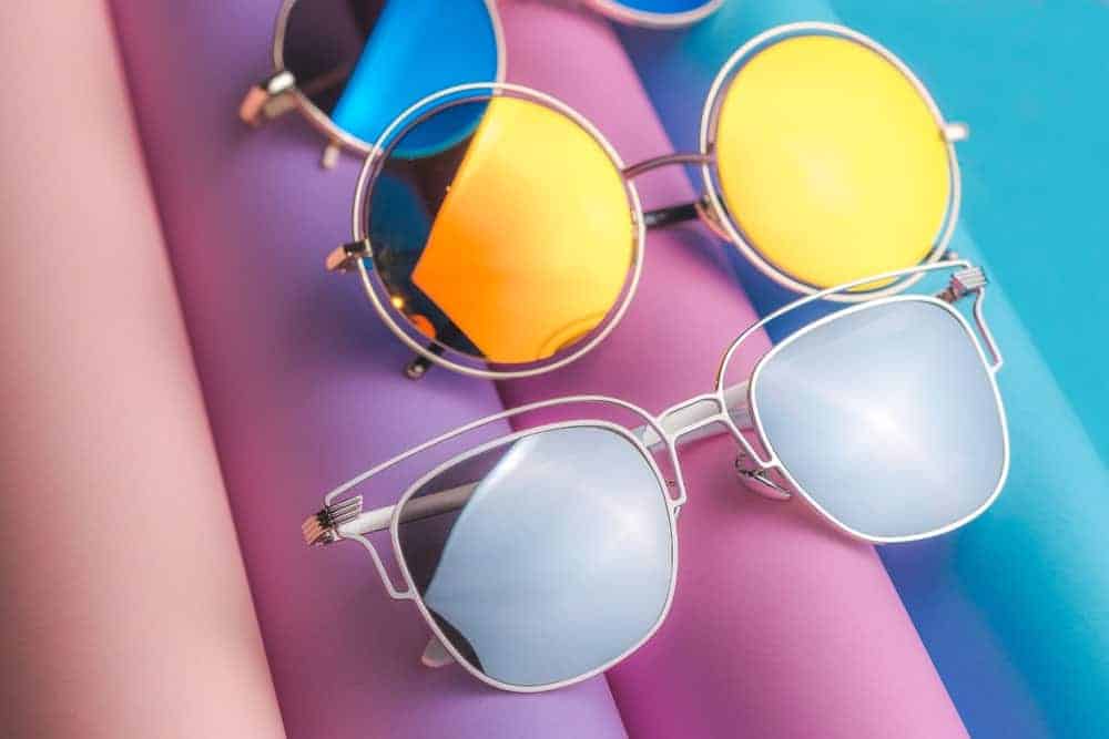 A close look at various pairs of sunglasses on a colorful surface.
