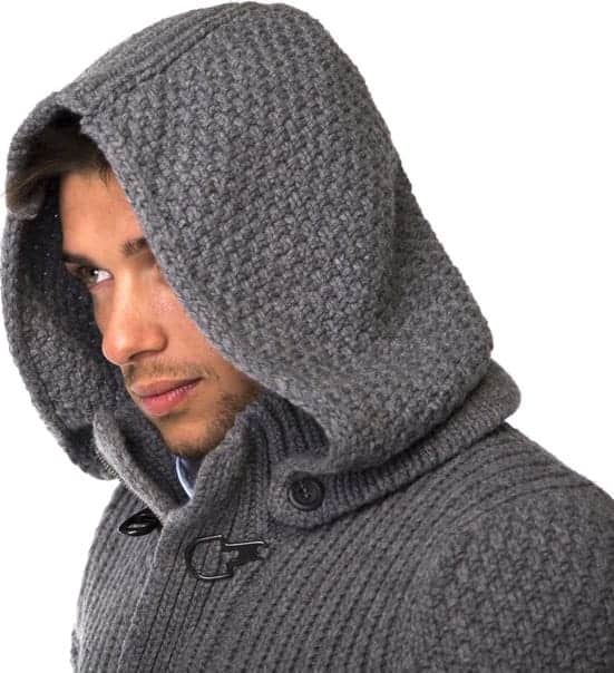 A close look at a man wearing a gray knitted sweatshirt with hood attachment.