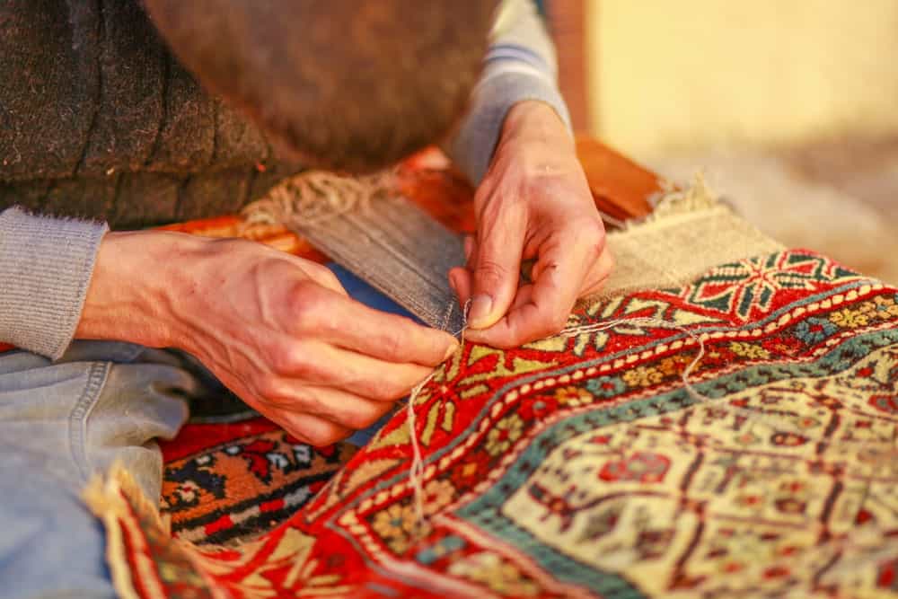 This is a close look at a man weaving a carpet.