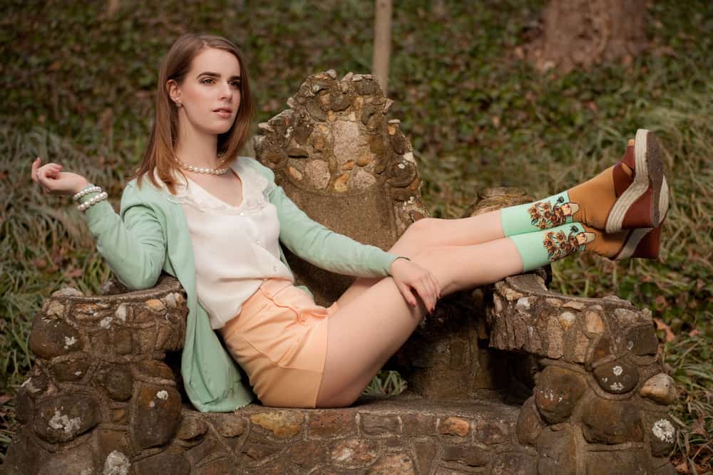 Woman in an art hoe style outfit sitting on a stone chair outdoors.