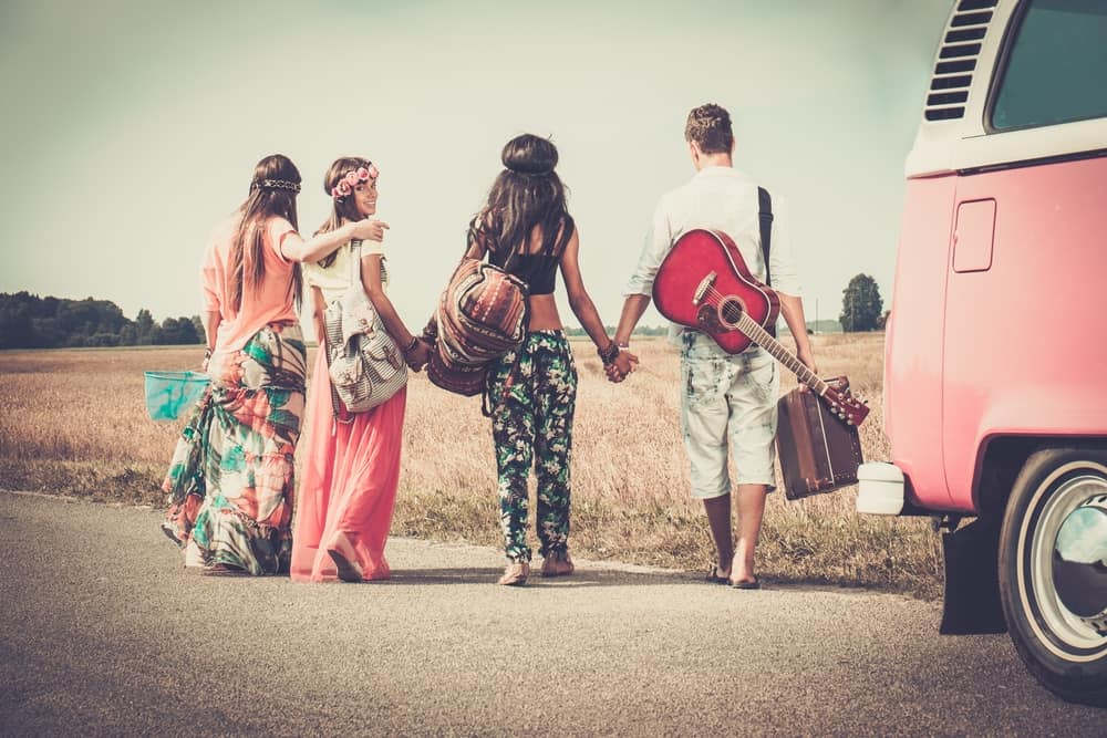 Hippie friends with luggage and guitar.