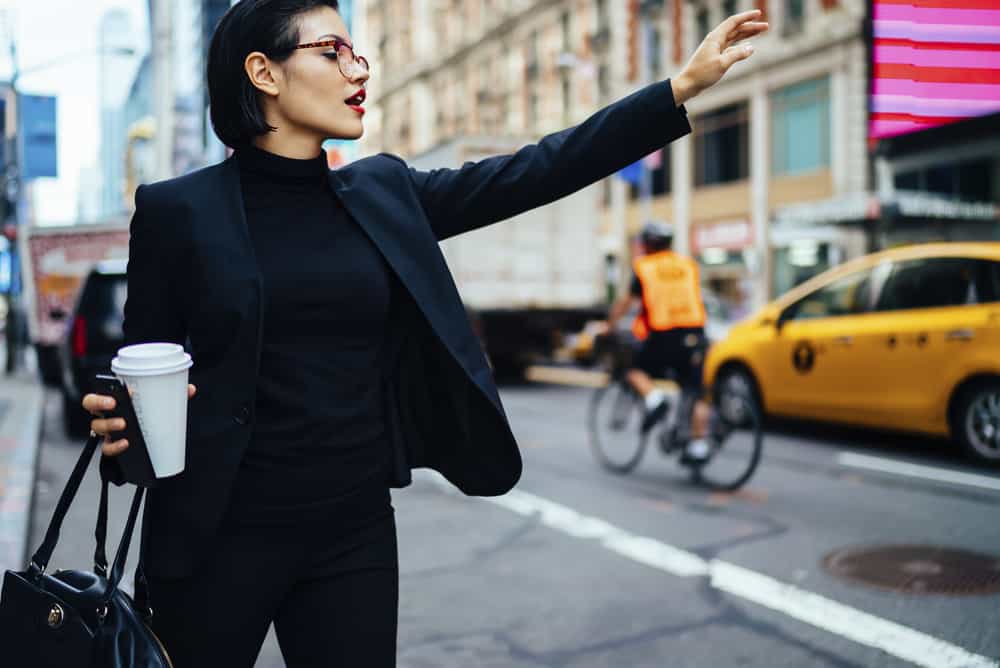 Woman in an NYC style outfit calling a cab.