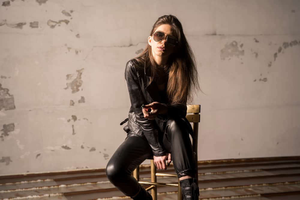 Rocker chic wearing leather jacket and pants sitting in an abandoned room.