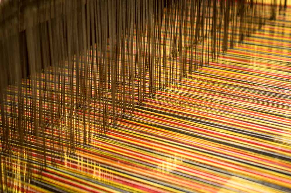 This is a close look at brocade fabric being weaved on a loom.