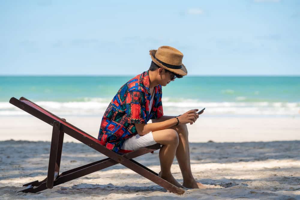 Man sitting on a wooden lounger near the beach.