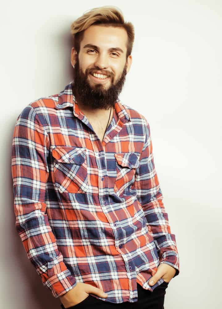 Bearded man wearing a checkered long sleeves polo.