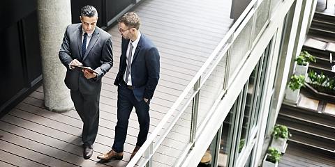 Two businessmen having discussion on the second-level balcony.