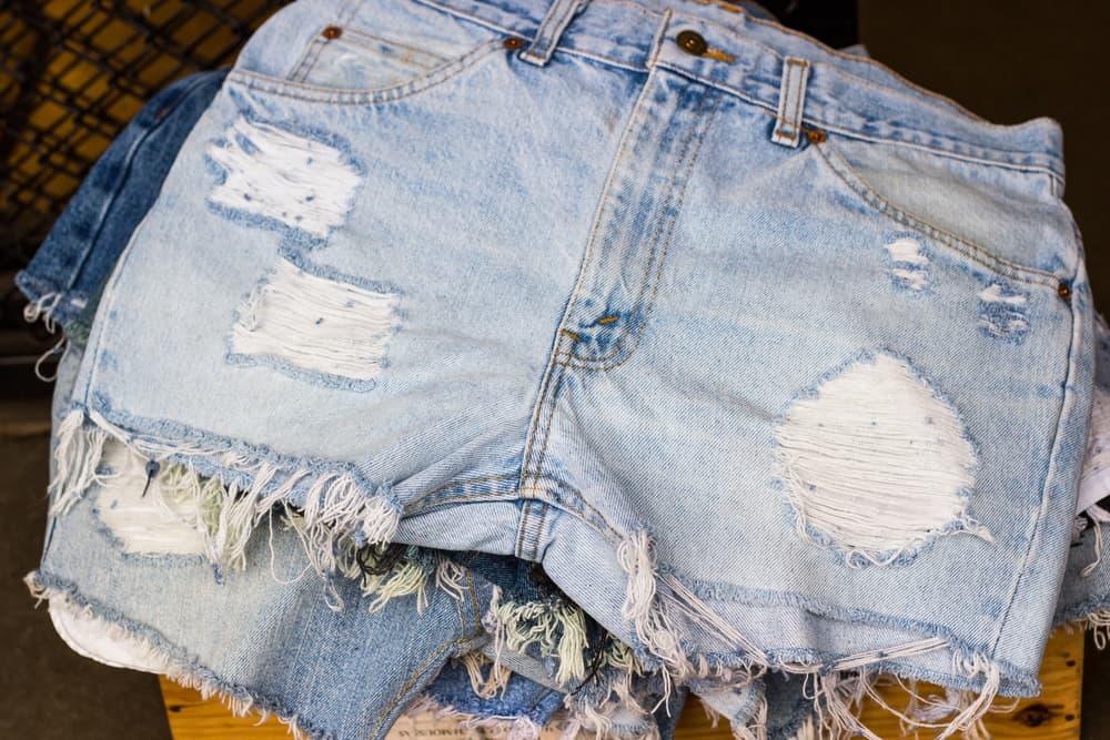 This is a close look at a stack of distressed and ripped jean shorts.