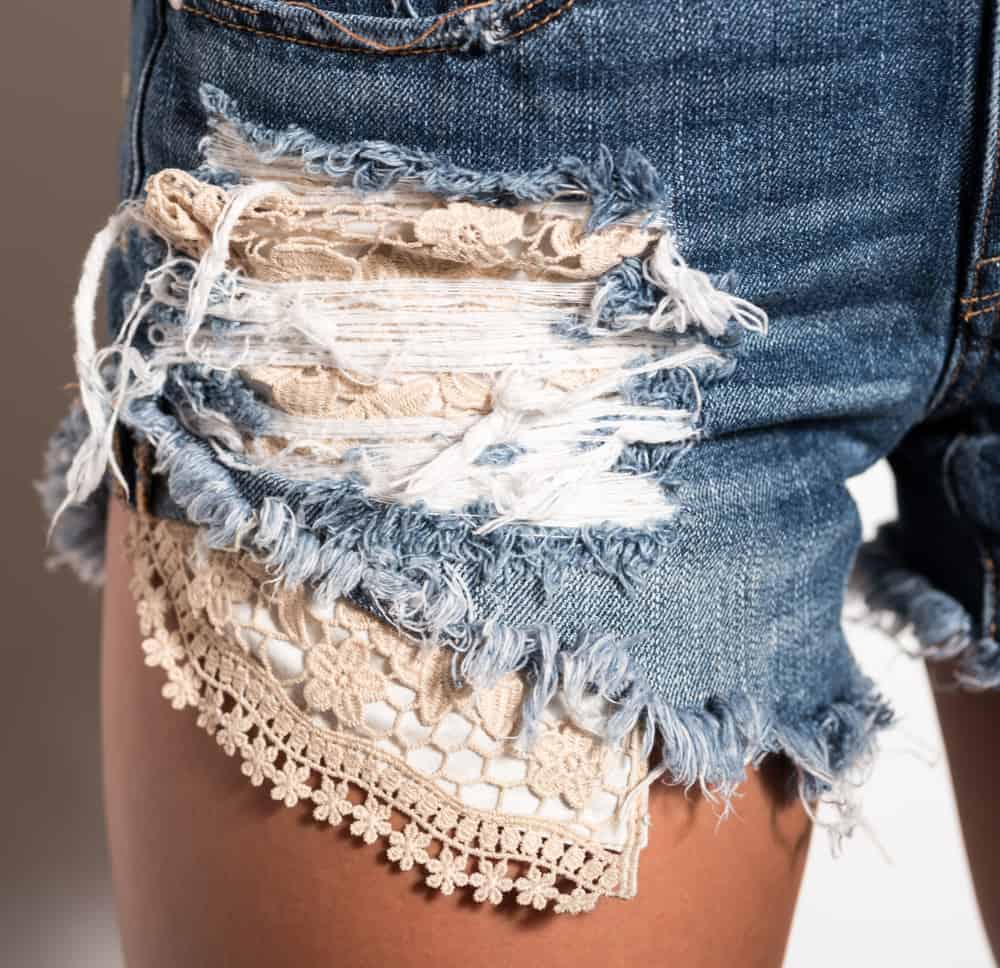 This is a close look at a woman wearing a pair of distressed jean shorts.