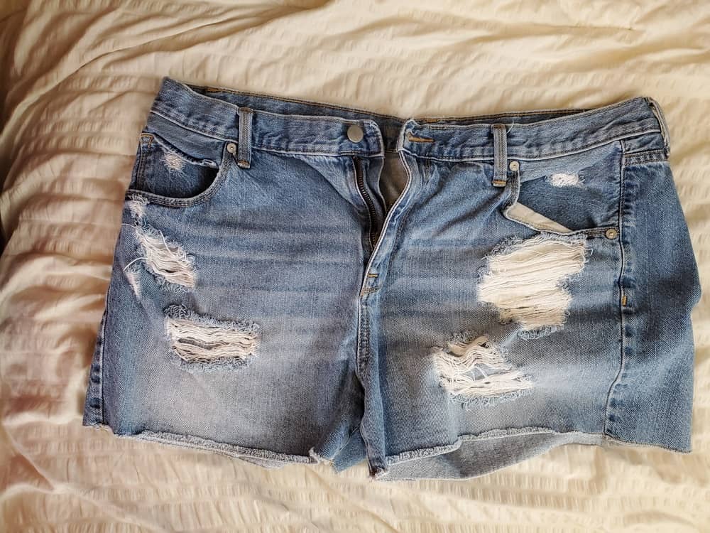 This is a close look at a pair of distressed jean shorts.