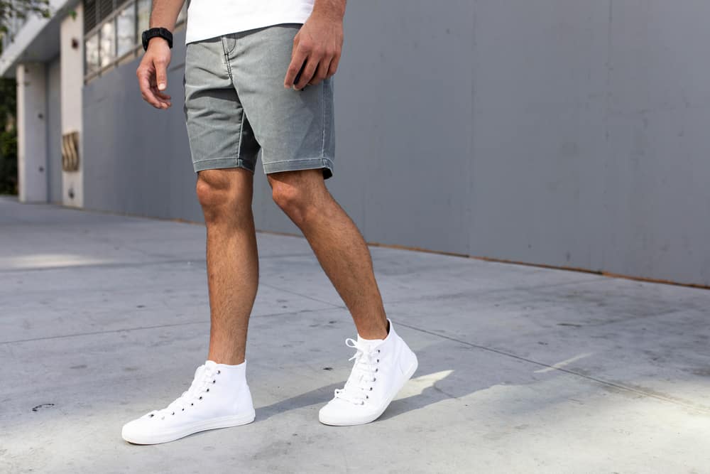 This is a close look at a man wearing a pair of shorts with his ankle-high sneakers.