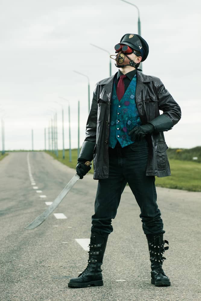 Man in steampunk style clothes poses on the road.