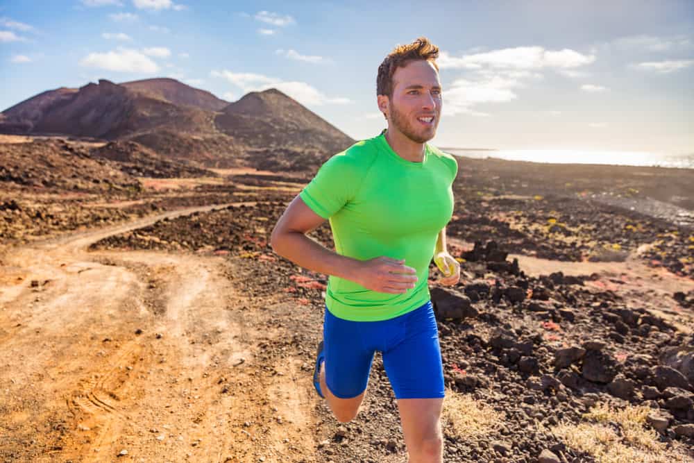 This is a close look at a man running on a mountain trail wearing a pair of compression shorts.