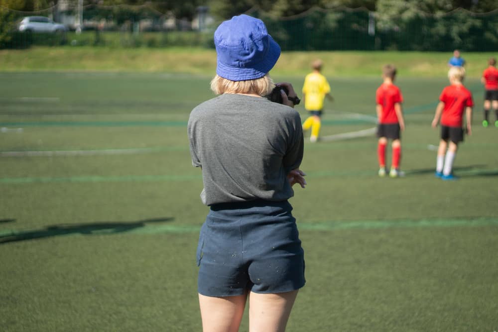 A woman watching a football match wearing soffe shorts.