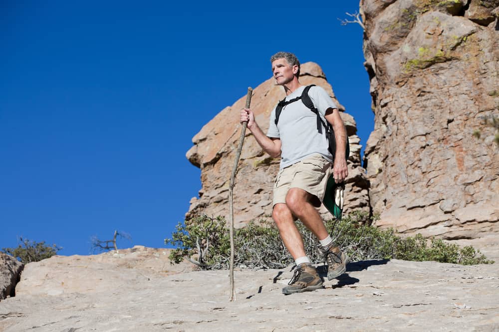 A man hiking on a mountain trail wearing desert boots.