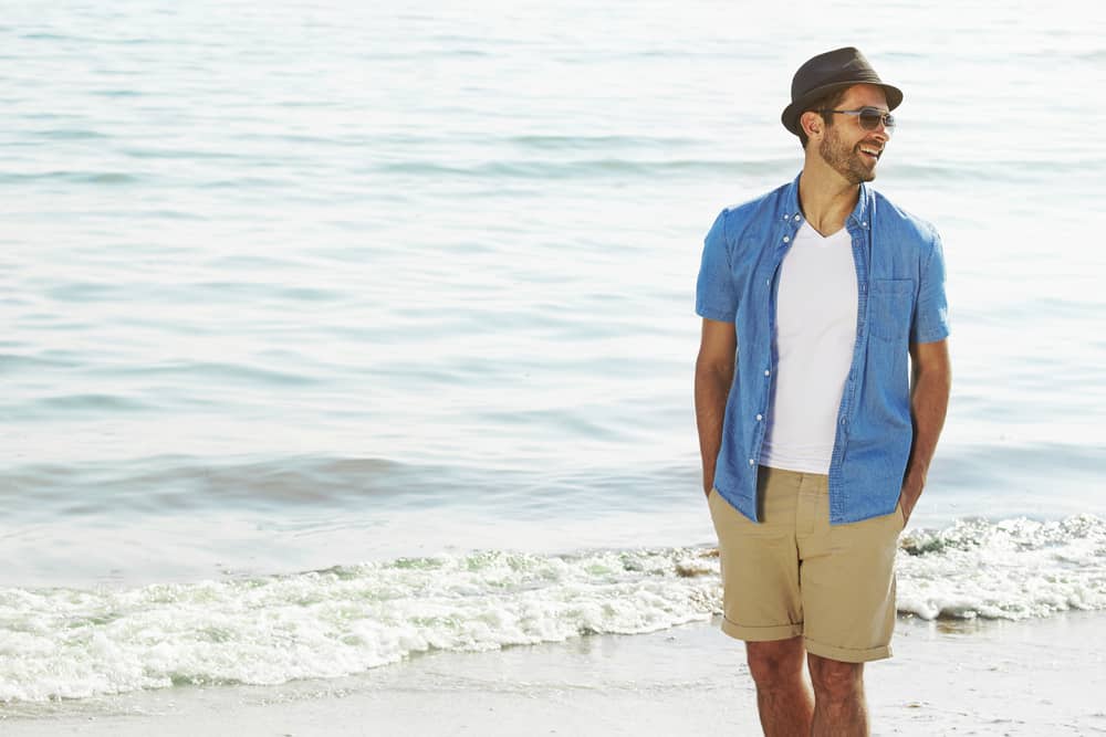 This is a close look at a man wearing a pair of khaki shorts at the beach.