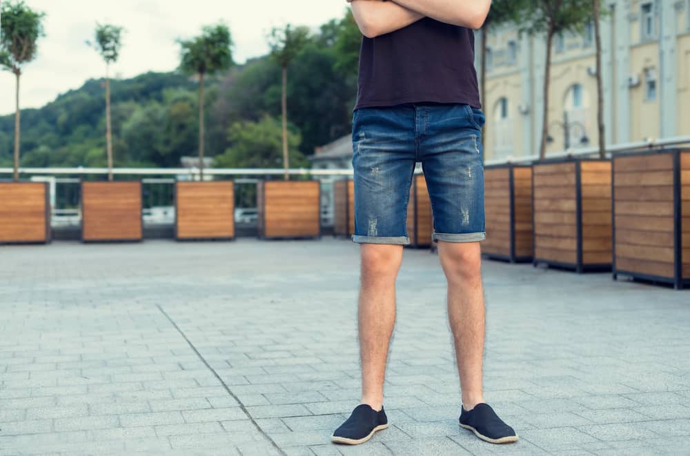 This is a close look at a man wearing a pair of jean shorts.