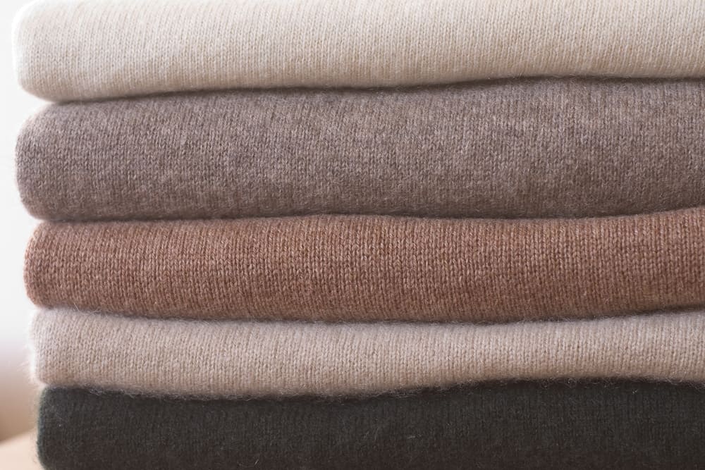 This is a close look at stacked and folded cashmere clothes with neutral tones.