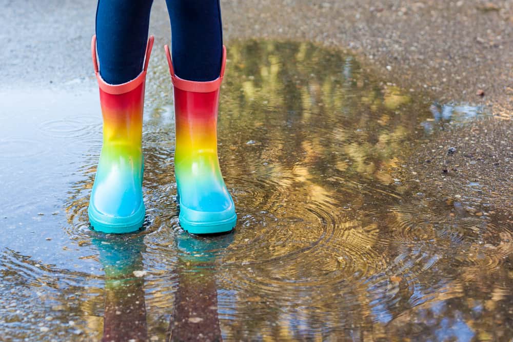 This is a close look at a child wearing a pair of rainbow rubber boots.