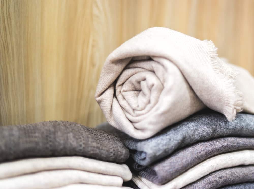 This is a close look at a stack of cashmere clothes with one rolled up on top.