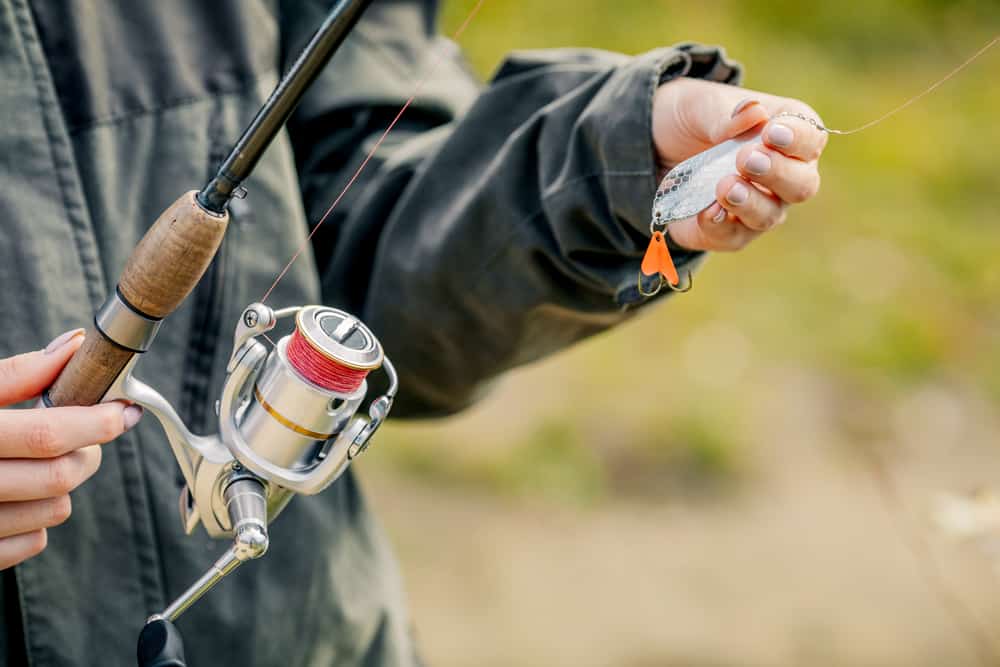 A man holding a fishing rod and wearing a black rain gear.