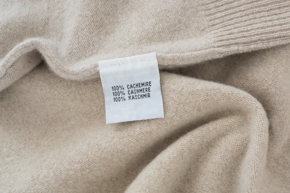 This is a close look at the tag of a sweater that depicts that it is 100 percent cashmere.