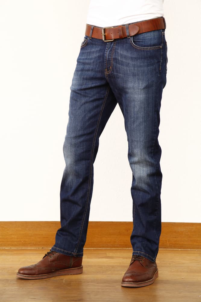 This is a close look at a man wearing jeans and brown leather shoes.