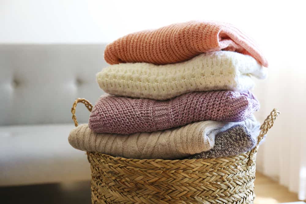 This is a look at folded and stacked sweaters in a basket.