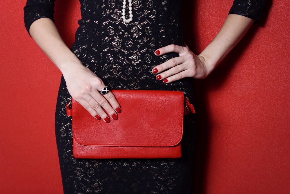 This is a close look at a woman wearing a little black dress that she paired with red accessories.
